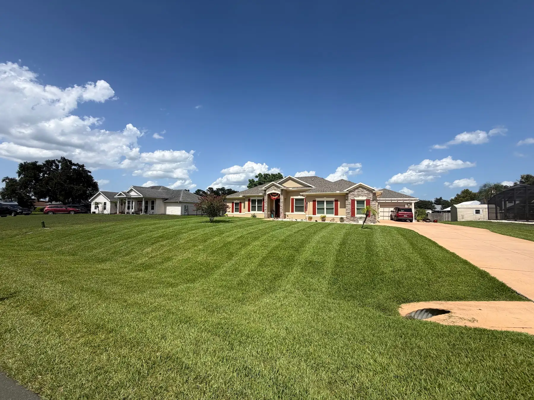 A freshly striped front lawn in front of a stone-front house
