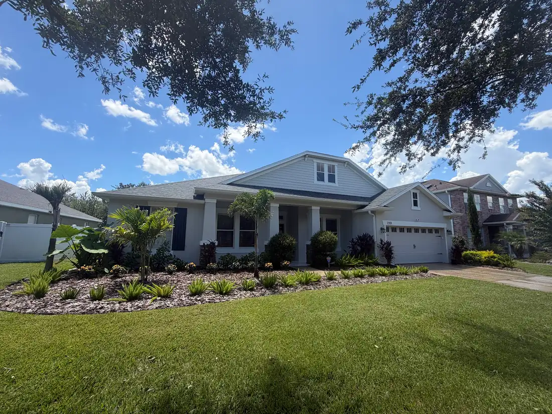 A new front bed of shrubs and palms along a house