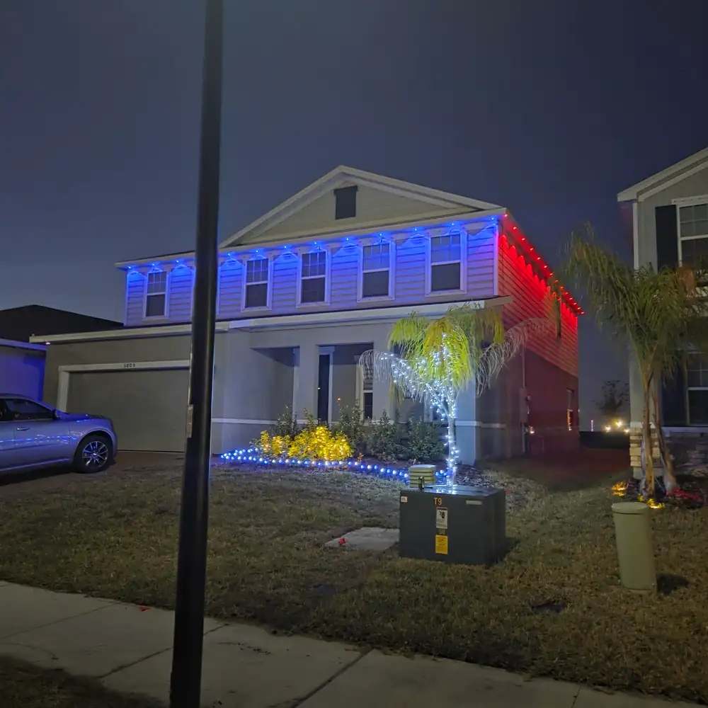 A two-story house lit red, white and blue at night