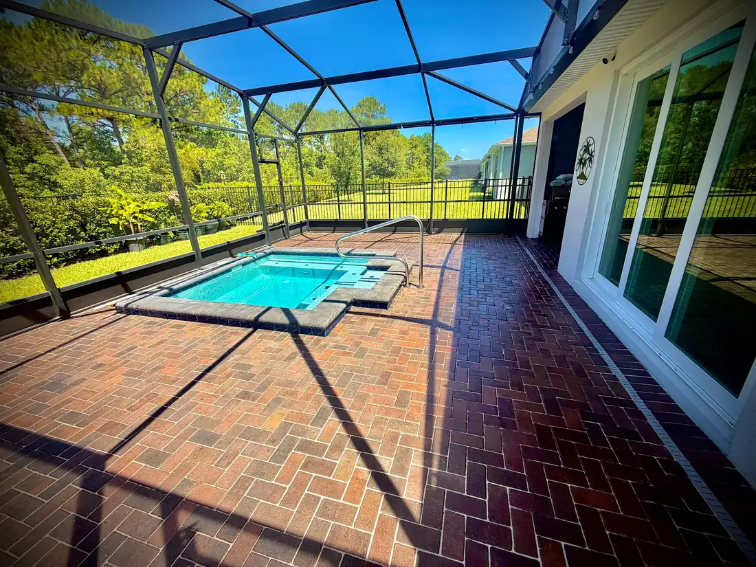 A brick paver deck around a screened spa